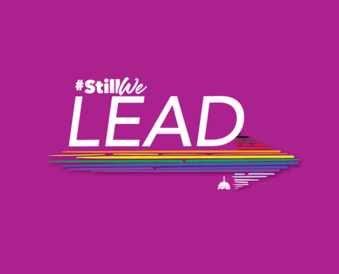 The image says #StillWe LEAD. #StillWe is smaller and justified to the left on top of the word LEAD, which is in all caps and white font. Below #StillWe LEAD is a progressive pride color arrow pointing to the right. The jagged lines that make up the arrow, start from the top with black, brown, red, orange, yellow, green, blue, purple, baby blue, white, then pink. Just below the arrow in the corner to the left of the arrow point, is the Capital Pride dome logo in white.